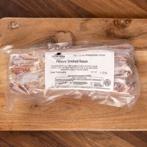 Packaged hickory-smoked bacon on a wooden cutting board with a white label visible on the packaging.