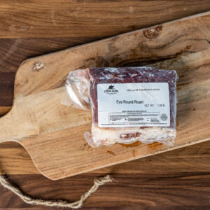 Vacuum-sealed eye round roast on a rustic wooden cutting board with a Fred's Farm label.