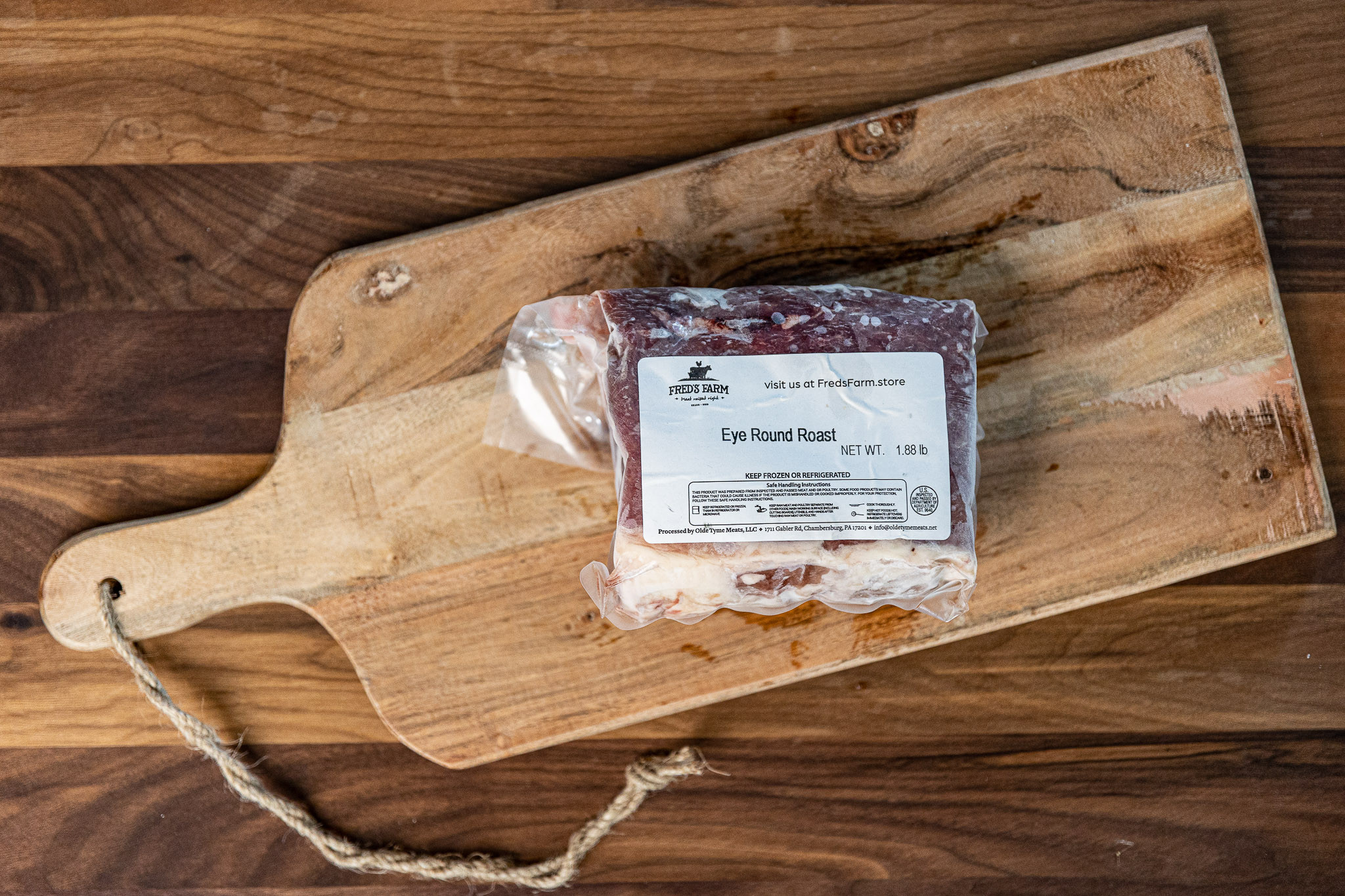 Vacuum-sealed eye round roast on a rustic wooden cutting board with a Fred's Farm label.