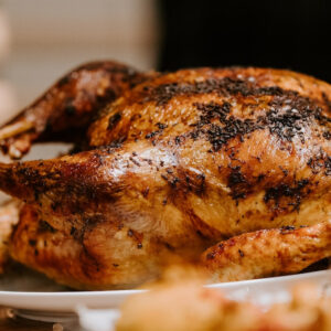 Golden brown roasted turkey on a white plate with crispy skin ready to serve.