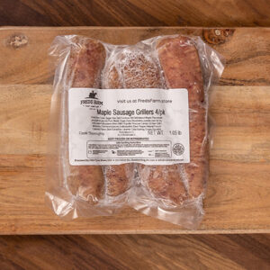 Vacuum-sealed bag containing four maple sausage grillers on a wooden cutting board with a label reading 'Maple Sausage Grillers 4 pk'