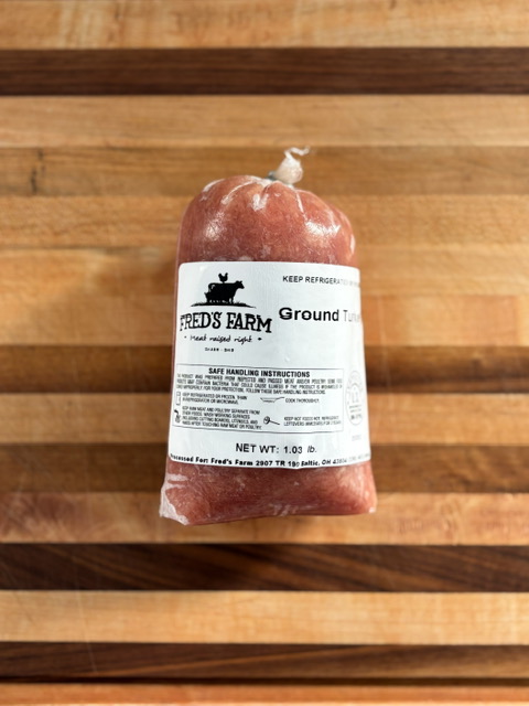 Ground sausage in red casing with Fred's Farm label resting on a wooden cutting board.