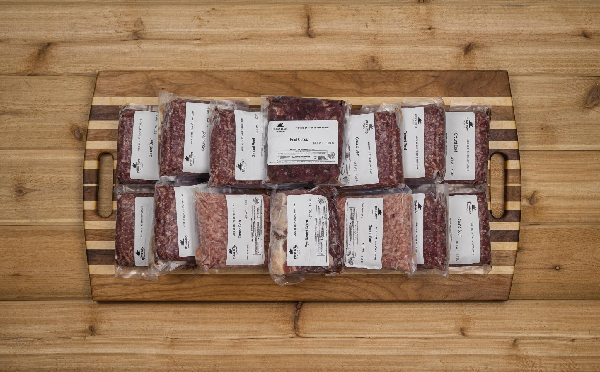 Vacuum-sealed bags of ground beef arranged on a wooden cutting board with labels visible on each package.