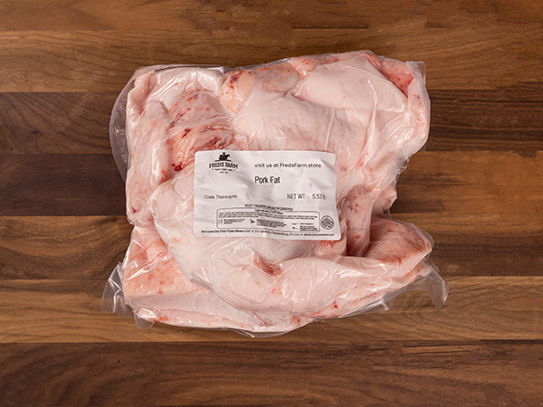 Vacuum-sealed bag of pork fat on a wooden surface, label reads Pork Fat.