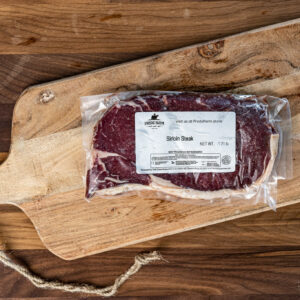 Vacuum-sealed sirloin steak on a rustic wooden cutting board with a rope handle nearby.
