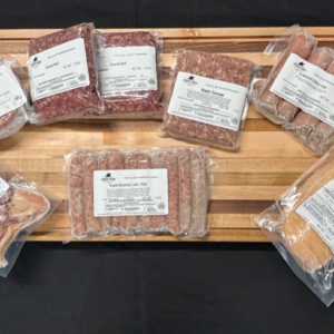 Assorted vacuum-sealed meat packages (sausages and burgers) arranged on a wooden cutting board.