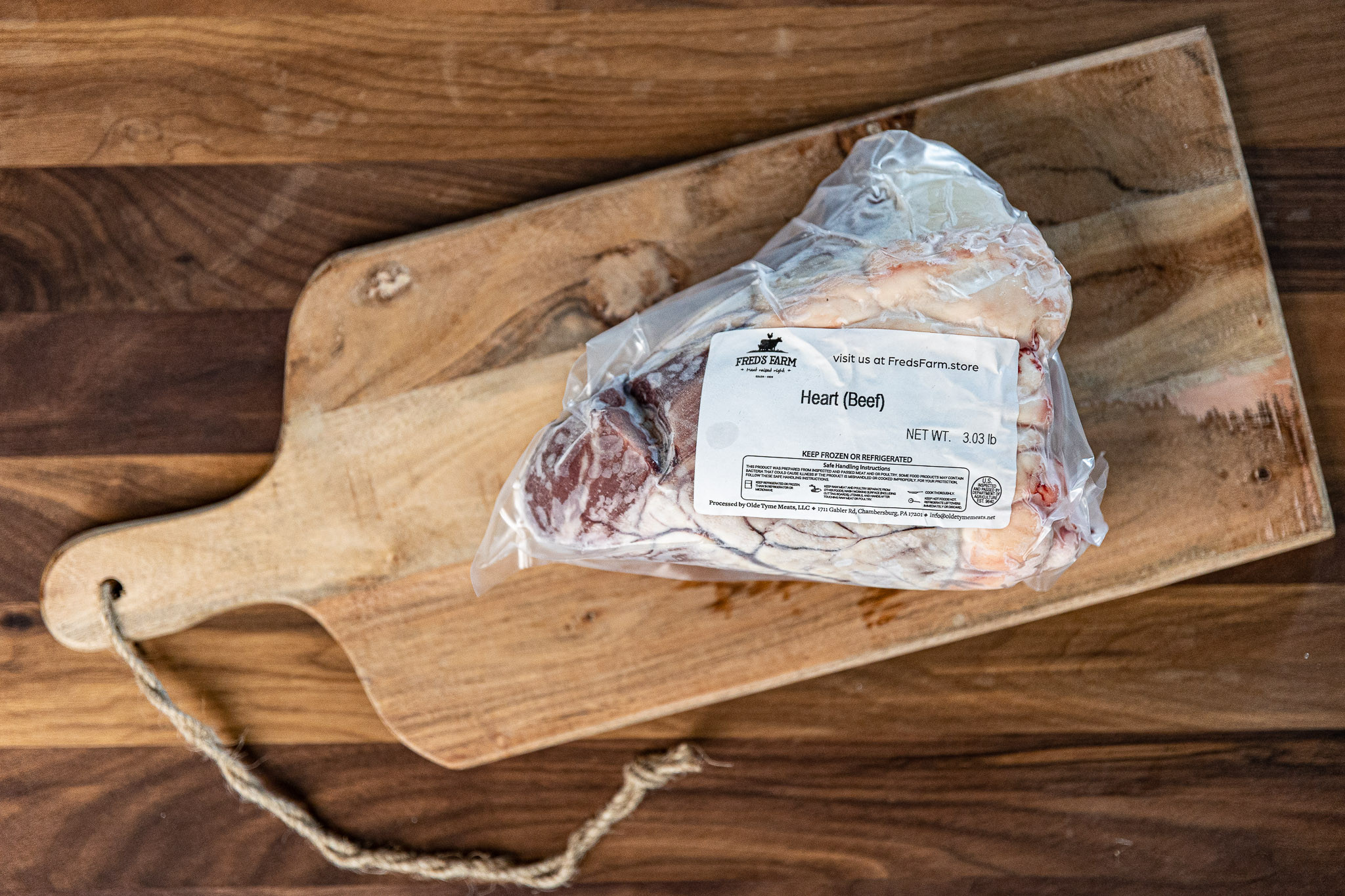 Vacuum-sealed beef heart with a label reading 'Heart (Beef)' on a wooden cutting board.