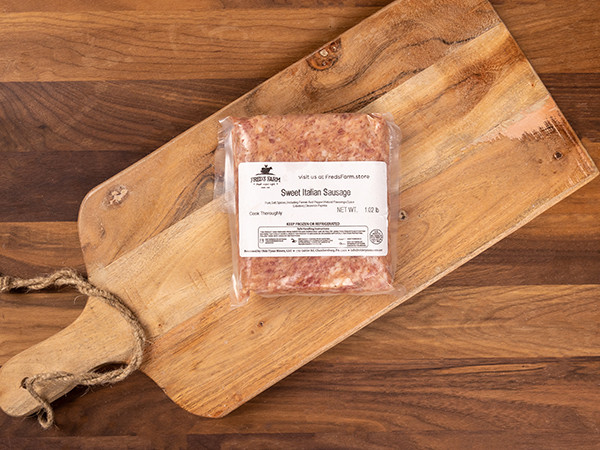 Vacuum-sealed Sweet Italian sausage on a wooden cutting board, label reads Sweet Italian Sausage (12 oz).