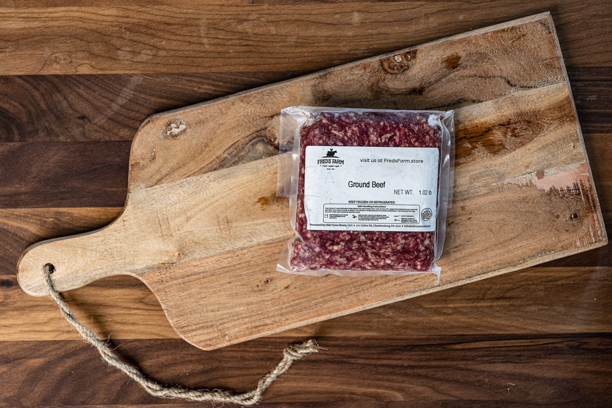 Vacuum-sealed ground beef on a wooden cutting board with a white label that reads Ground Beef on the package.