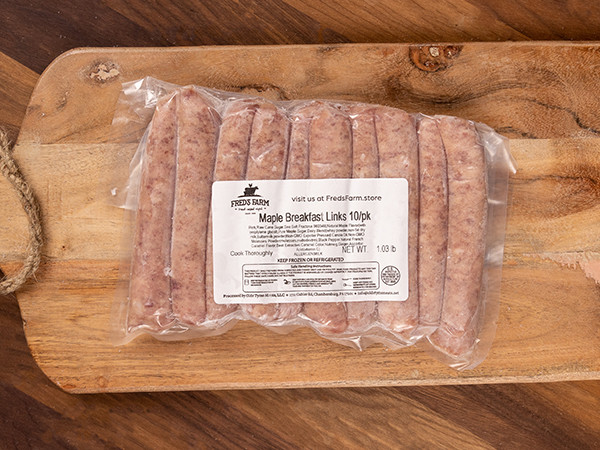 Vacuum-sealed pack of maple breakfast sausage links on a wooden cutting board, label reads 'Maple Breakfast Links 10/pk'.