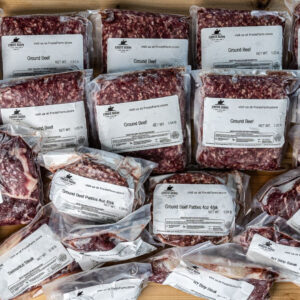 Vacuum-sealed packets of ground beef arranged on a wooden surface, labels visible.