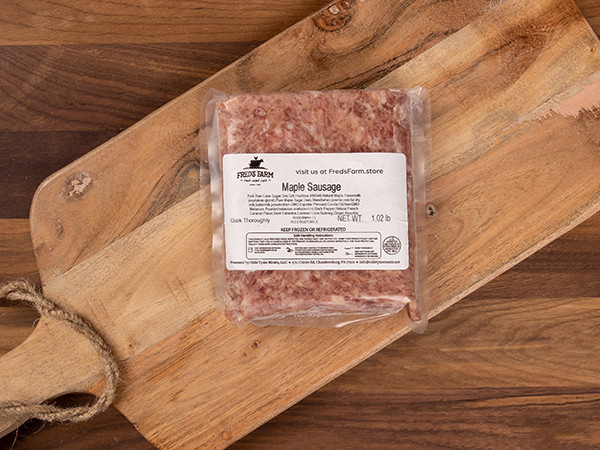 Vacuum-sealed maple sausage on a wooden cutting board, Far from the label visible on the package (brand: Fred's Farm).