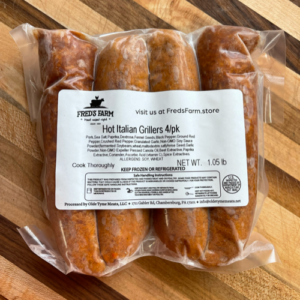 Four hot Italian sausages in a clear vacuum-sealed package with a Fred's Farm label, shown on a wooden surface.