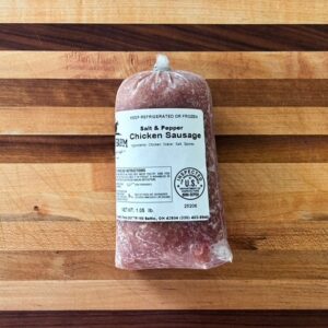 Vacuum-sealed Salt & Pepper Chicken Sausage on a striped wooden cutting board (weight 1.05 lb).