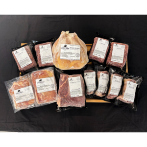 Assortment of vacuum-sealed meat packages on a wooden tray, dominated by a central whole chicken.