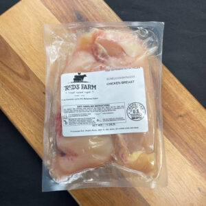 e4f6dc61-c10b-42bc-ae2a-c4268502a9f9 - Fred's Farm Vacuum-sealed chicken breast from Red's Farm on a wooden cutting board, ready to thaw or cook.