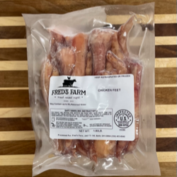Vacuum-sealed bag of chicken feet from Freda's Farm on a wooden table.