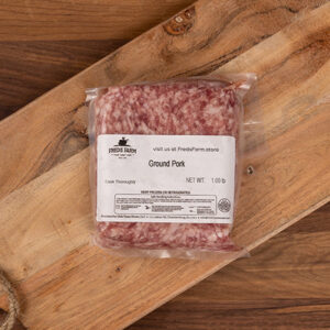 Vacuum-sealed pack of ground pork labeled Ground Pork on a wooden cutting board.