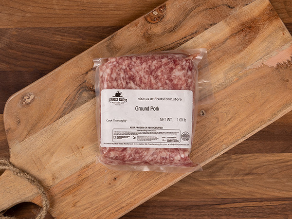 Vacuum-sealed pack of ground pork labeled Ground Pork on a wooden cutting board.