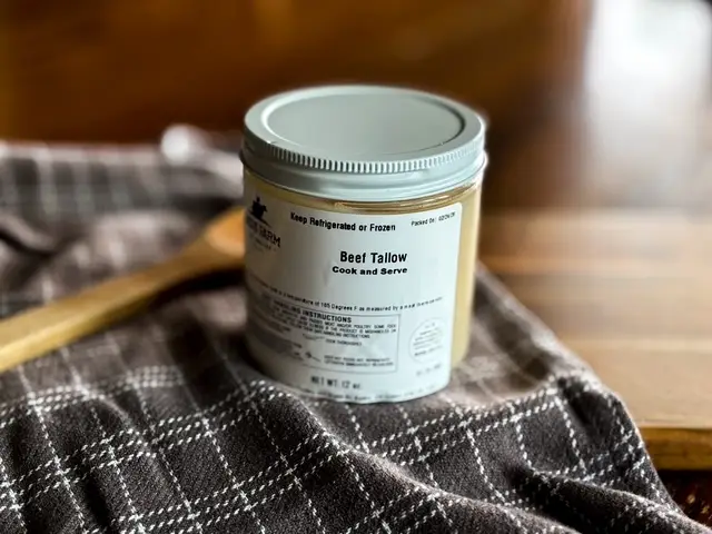 Beef tallow jar with a metal lid on a plaid cloth, labeled 'Beef Tallow' and 'Cook and Serve'.