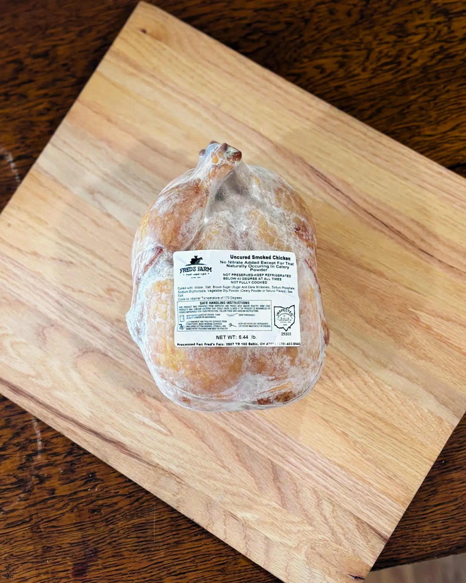 Uncured smoked chicken sausage on a light wooden cutting board with a label visible on the packaging.